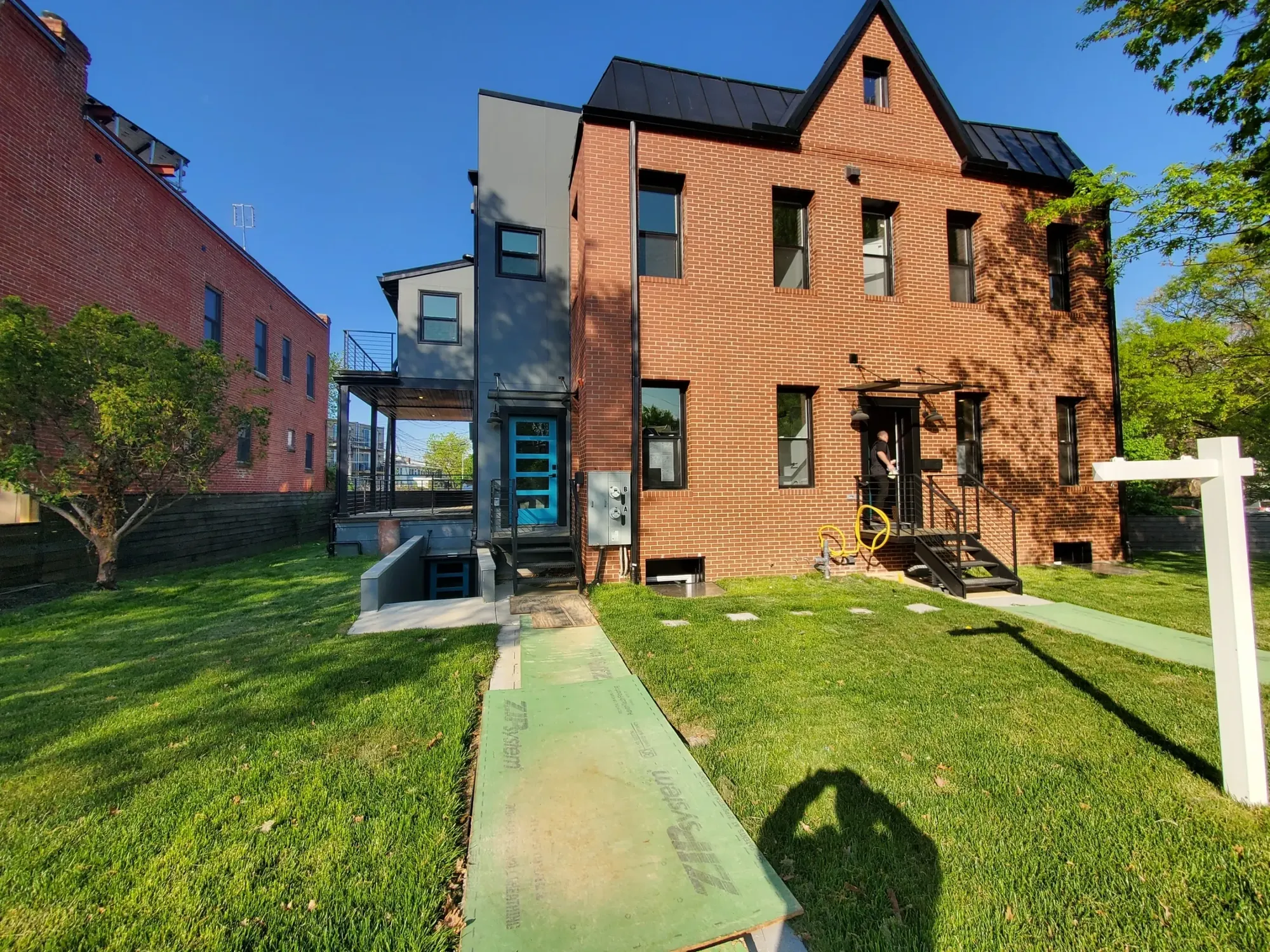Red-brick house with solar panels and a protection board across the lawn.