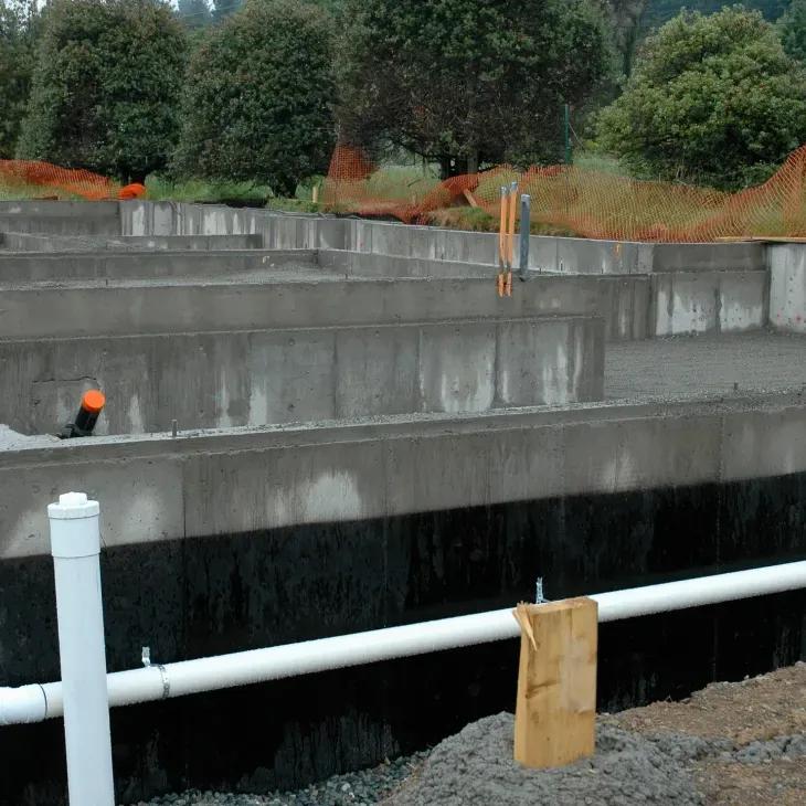 Cast-in-place concrete foundation walls with waterproofing at the base.