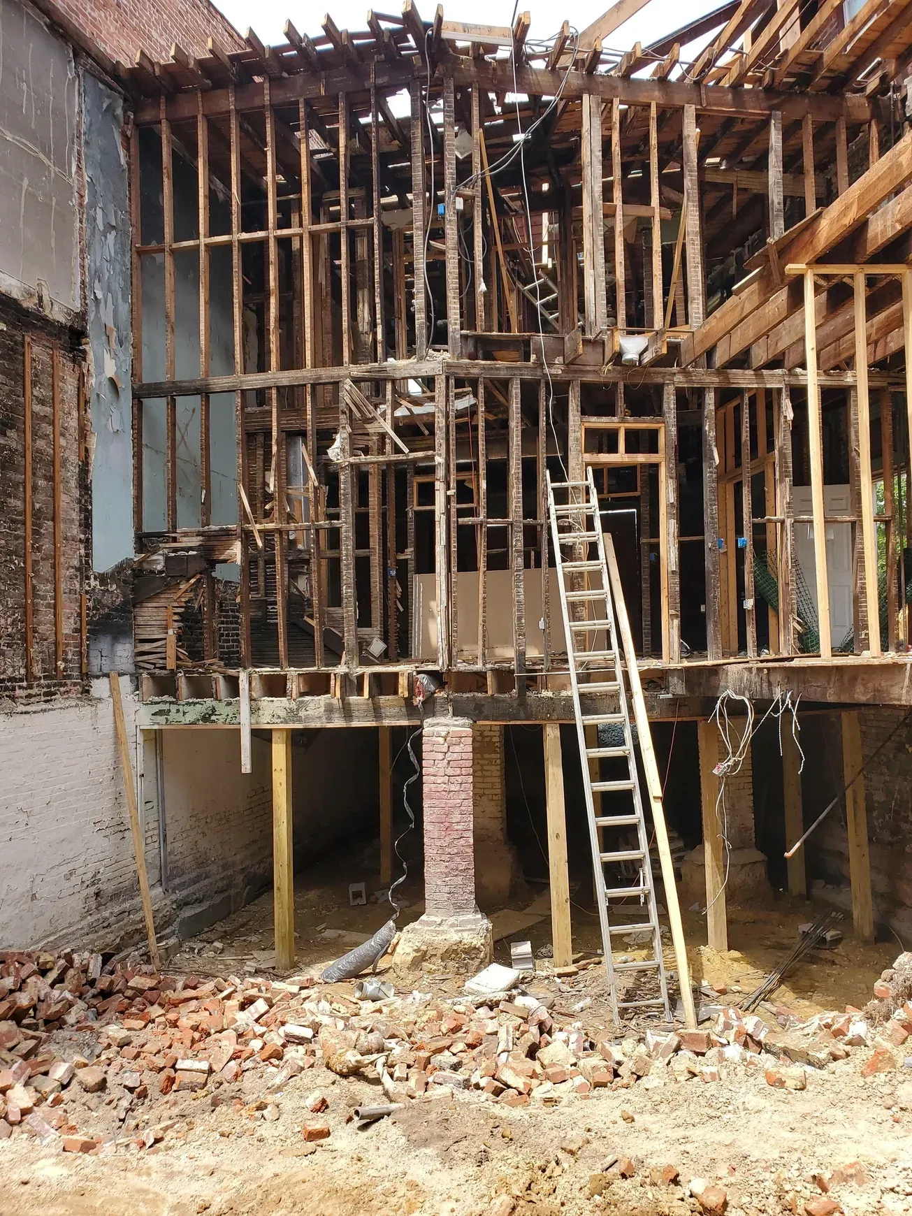 Open wood framing of a gutted building, with a ladder and rubble.