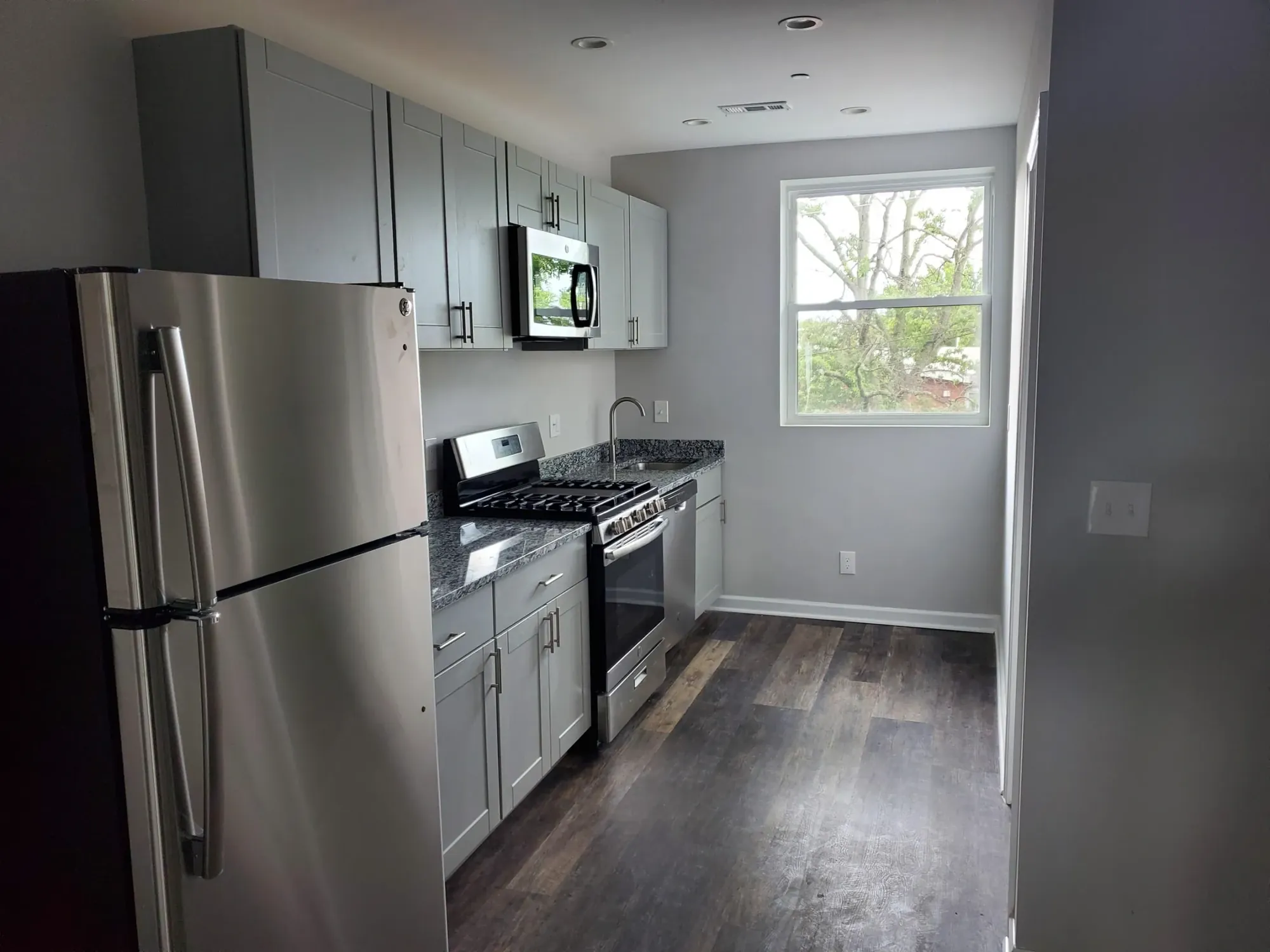 Galley kitchen with gray cabinets and stainless appliances.