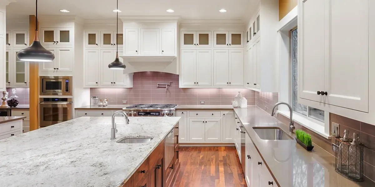 White kitchen with a granite island and tiled backsplash.
