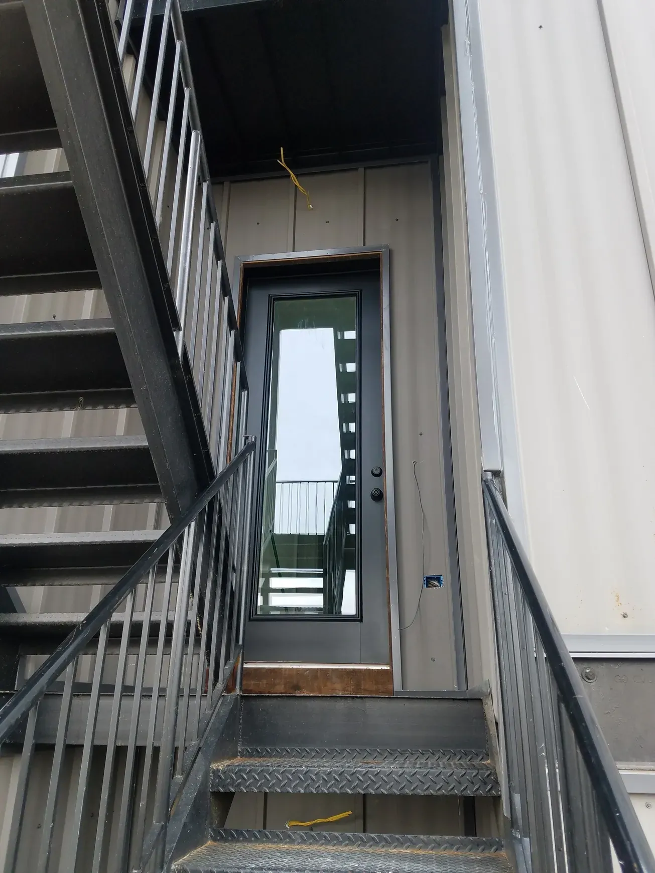 Metal exterior stair and landing at a glazed door.